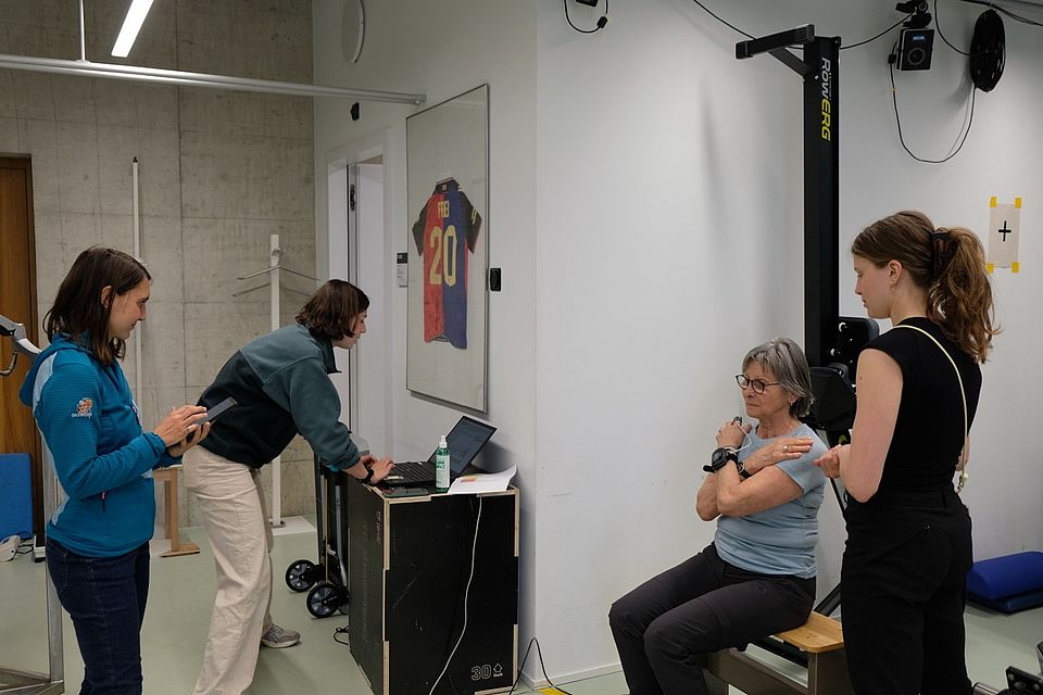 Unsere Probandin beim Sit-to-Stand Test, zusammen mit dem INCLUDE Team Larissa Hänsli, Noemie Marti, und Sierra Arn